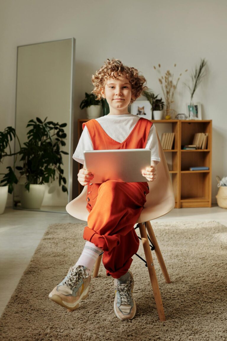 Smiling child with curly hair using a tablet in a modern home interior.